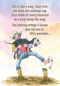 Humorous greeting card featuring a cartoon cowboy struggling to carry a calf, with motivational text about life's journey and lessons, set against a watercolor background.