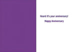 Inside of a humorous anniversary card, with simple text reading 'Heard it's your anniversary! Happy Anniversary' in a purple font on a white background, suitable for celebrating a milestone.