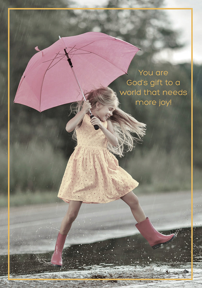 Young girl in yellow dress and pink boots joyfully jumping in a puddle with a pink umbrella. Religious birthday greeting card for a child, featuring text 'You are God's gift to a world that needs more joy!'.