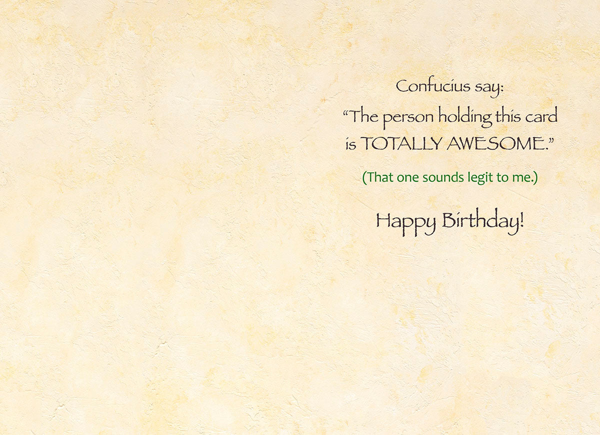 Inside view of a funny birthday card, revealing an inner message 'Confucius say: The person holding this card is TOTALLY AWESOME.' followed by '(That one sounds legit to me.) Happy Birthday!' against a textured, light cream background.