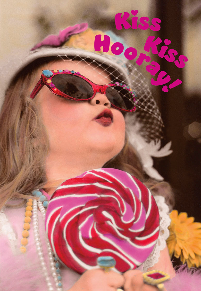 A cute young girl wearing red sequined sunglasses and a veiled hat, puckering up for a kiss while holding a large pink and white swirled lollipop, with "Kiss Kiss Hooray!" text.