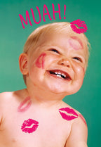 Joyful baby with multiple pink lipstick kisses on their cheeks, forehead, and shoulder, smiling broadly against a vibrant teal background. The word 'MUAH!' in pink capital letters is above their head, perfect for a cute Valentine's Day greeting card for a child.