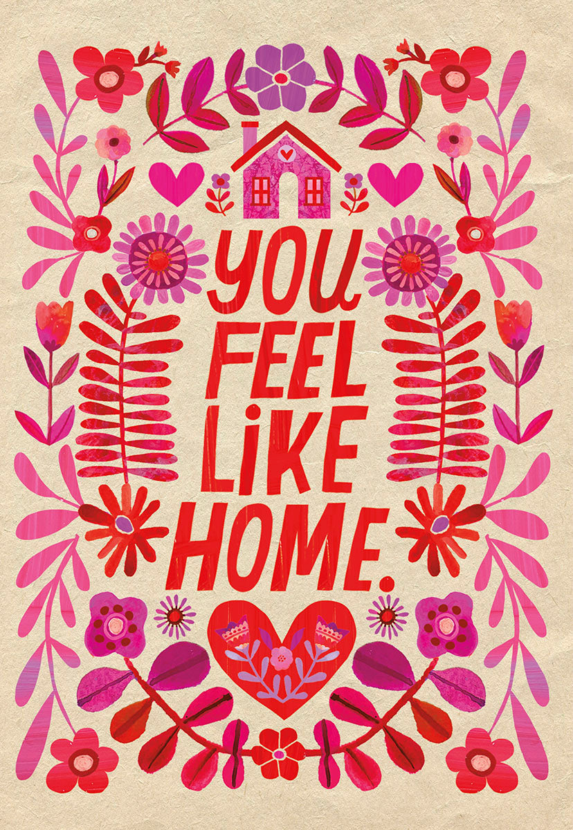 Front of a folk art style greeting card with a colorful house, hearts, and floral designs in pink, red, and purple, featuring the heartfelt message 'YOU FEEL LIKE HOME' for a spouse.