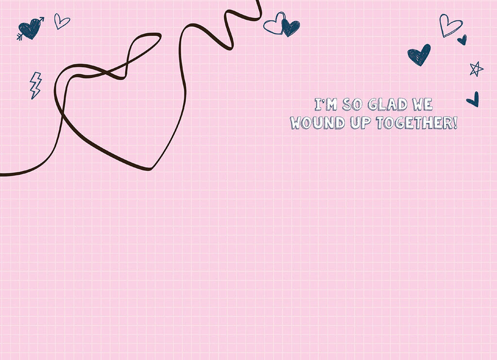 Inside of a retro romantic greeting card on a light pink grid background. A dark brown string forms a heart shape, with text 'I'm so glad we wound up together!' and scattered dark blue hearts.