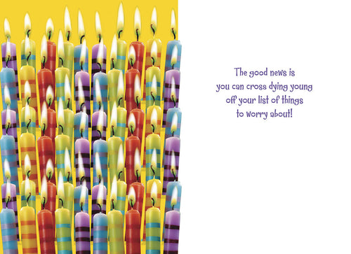 Inside of a humorous birthday card showing a dense arrangement of lit colorful striped candles on the left side, with a witty message on the right: 'The good news is you can cross dying young off your list of things to worry about!'