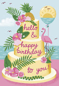 Vibrant tropical birthday greeting card featuring a three-tier cake with pineapple, hibiscus, palm leaves, and a pink flamingo holding an ocean sunset balloon. Front reads 'hello & happy birthday to you!'