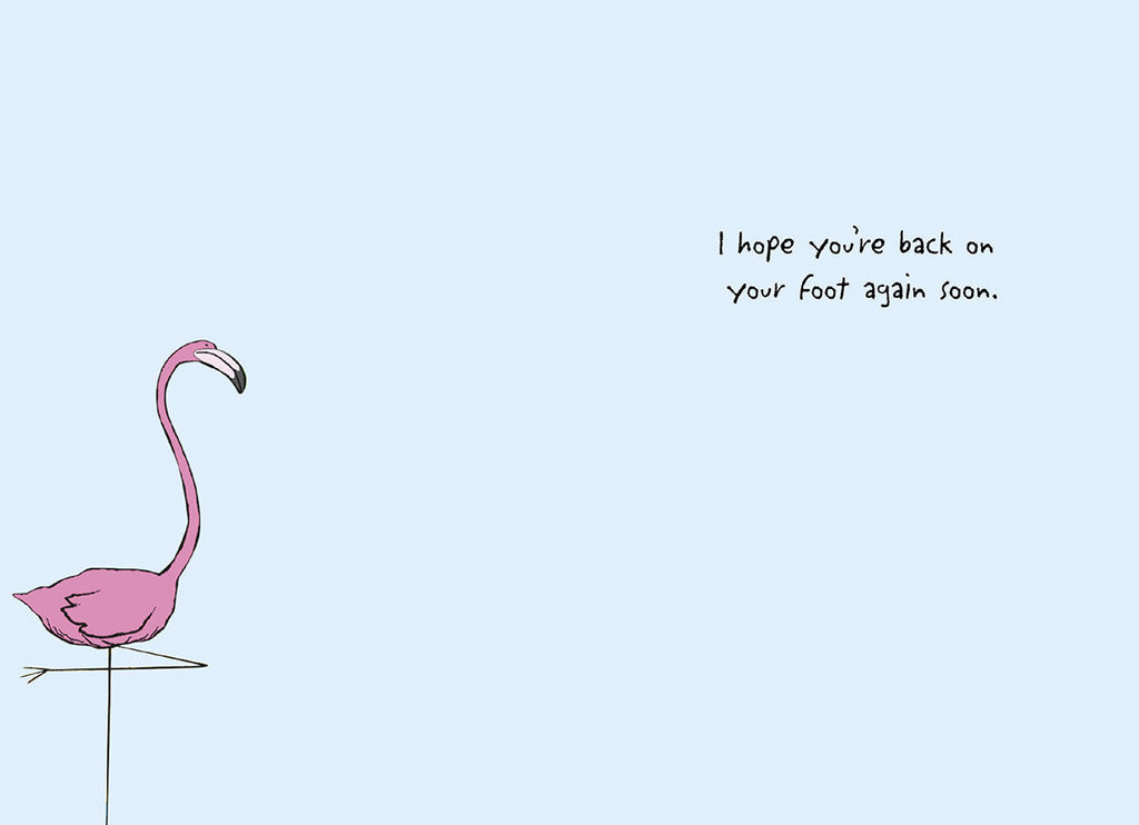 Inside of a humorous flamingo greeting card with one pink flamingo standing and the text 'I hope you're back on your foot again soon' for a speedy recovery message.