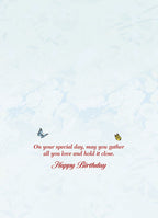 Inside of a heartfelt birthday greeting card with a thoughtful message in elegant red script: 'On your special day, may you gather all you love and hold it close. Happy Birthday.' Accented by small blue and yellow butterflies.