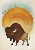 Front of an encouraging greeting card featuring a majestic brown bison silhouette against a warm orange sun, with the words 'THINKING OF YOU...' in an arc above.