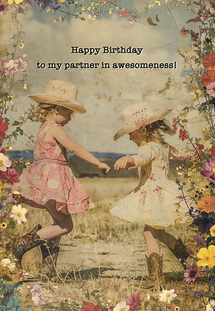 Vintage style birthday card featuring two joyful young girls in cowboy hats dancing among vibrant wildflowers, with text 'Happy Birthday to my partner in awesomeness!'