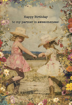 Vintage style birthday card featuring two joyful young girls in cowboy hats dancing among vibrant wildflowers, with text 'Happy Birthday to my partner in awesomeness!'