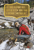 Humorous gold prospector greeting card, featuring a grizzled miner panning for gold next to a patient donkey by a mountain stream. The front of the card playfully declares: 'IF I WAS TO STRIKE GOLD, YOU'D BE GETTIN' MORE THAN A BIRTHDAY CARD FROM ME...'. Perfect for sending funny well wishes to a friend or sibling.