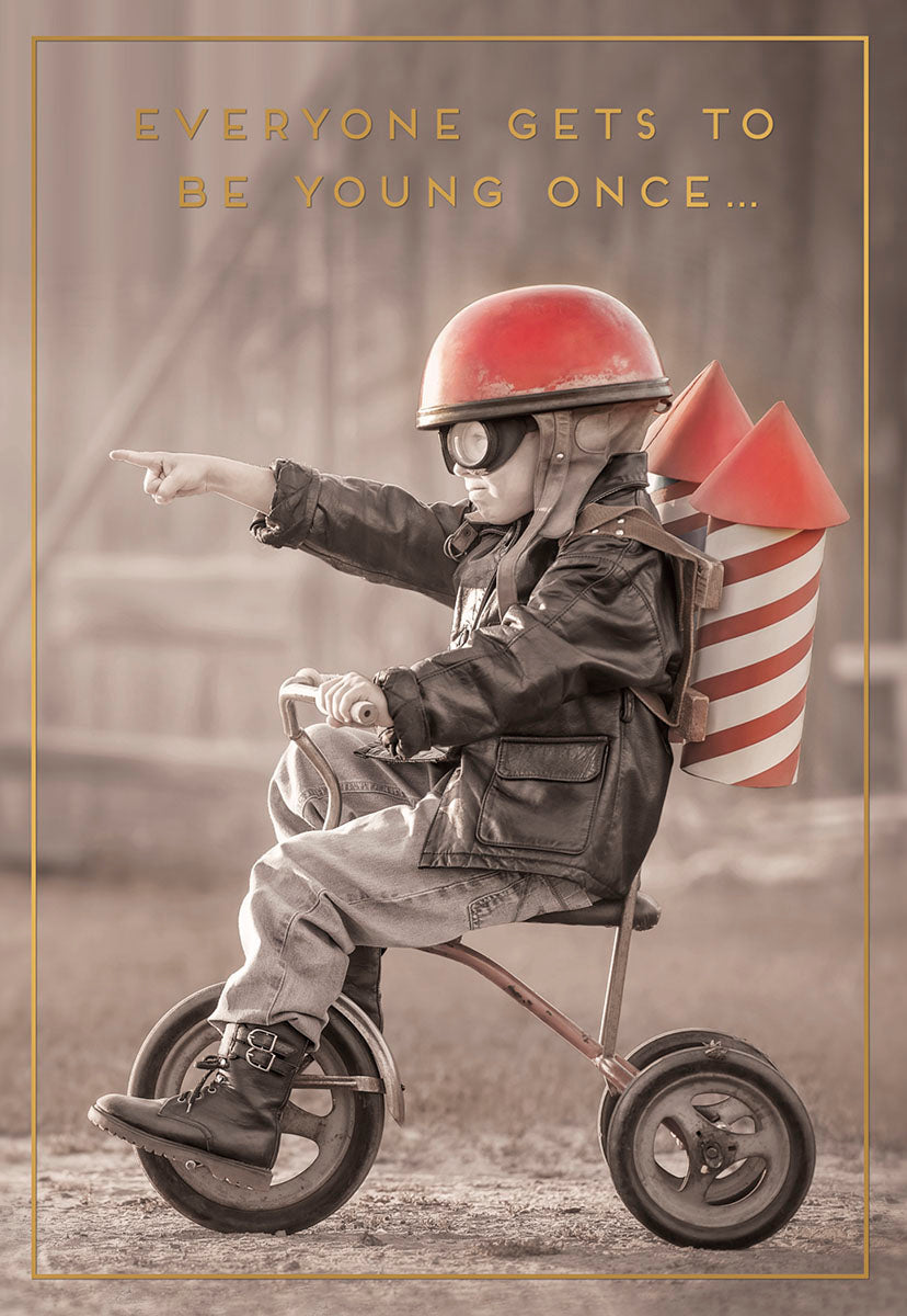 Vintage-style greeting card featuring a child in a pilot helmet and rocket backpack riding a tricycle, pointing with determination. Text reads 'EVERYONE GETS TO BE YOUNG ONCE...'. Perfect for a humorous, nostalgic card.