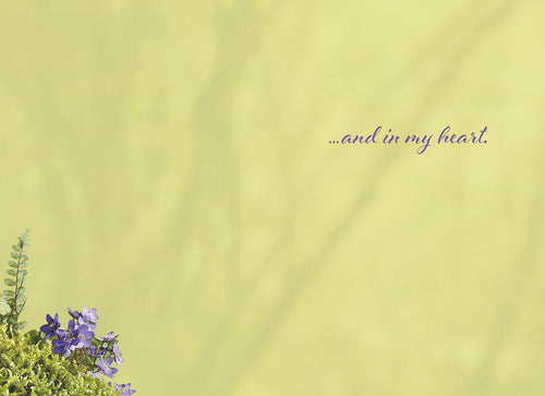 Inside of a greeting card with a light yellow-green background, subtle purple wildflowers in the bottom left, and text '...and in my heart.'