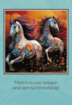 Front of a vibrant friendship greeting card featuring two artistically embellished horses galloping against a fiery orange and blue sky. Text reads: "Here's to our unique and special friendship!"
