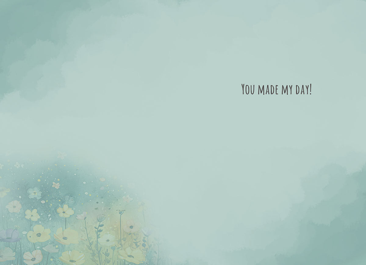 Inside of a greeting card with a light teal background and subtle watercolor floral elements in the bottom left corner. The message 'YOU MADE MY DAY!' is printed in a casual font on the right side.