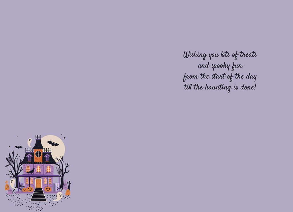 Inside of a cute Halloween greeting card with a small haunted house illustration and a printed message: 'Wishing you lots of treats and spooky fun from the start of the day till the haunting is done!' on a light purple background.