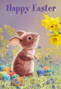 Cute brown bunny looking at yellow daffodils with colorful patterned eggs in spring grass, ideal for an Easter greeting card for kids.