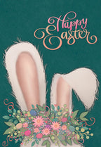 Front of a cute Easter greeting card featuring fluffy white bunny ears emerging from a vibrant bouquet of pink flowers, green leaves, and pastel eggs, set against a dark teal background. The words "Happy Easter" are written in decorative pink and orange script.