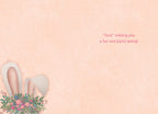 Inside of a light peach colored greeting card with a small illustration of white bunny ears with a floral and egg bouquet in the bottom left corner. The right side of the card features the sweet, punny message: '"Ears" wishing you a fun and joyful spring!'.