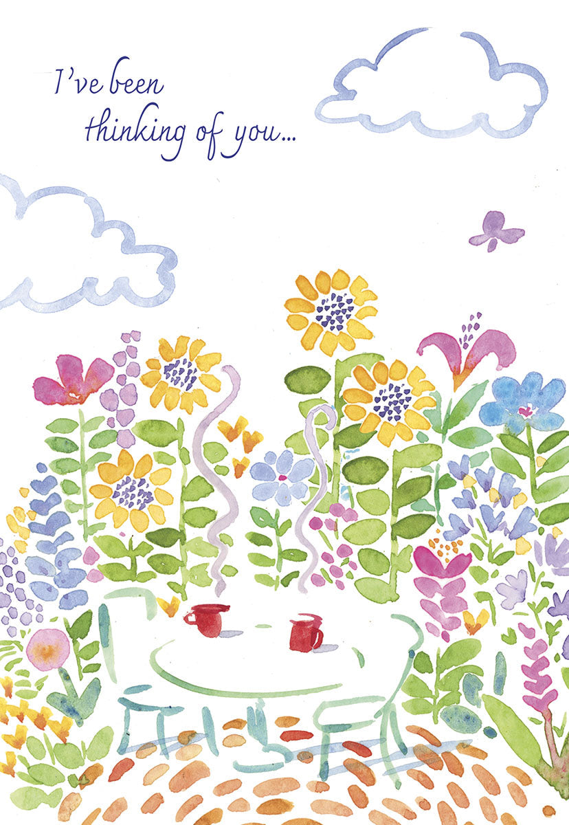 Front of a 'Thinking of you' card, depicting a cozy garden scene with flowers, a table, and two steaming coffee cups.