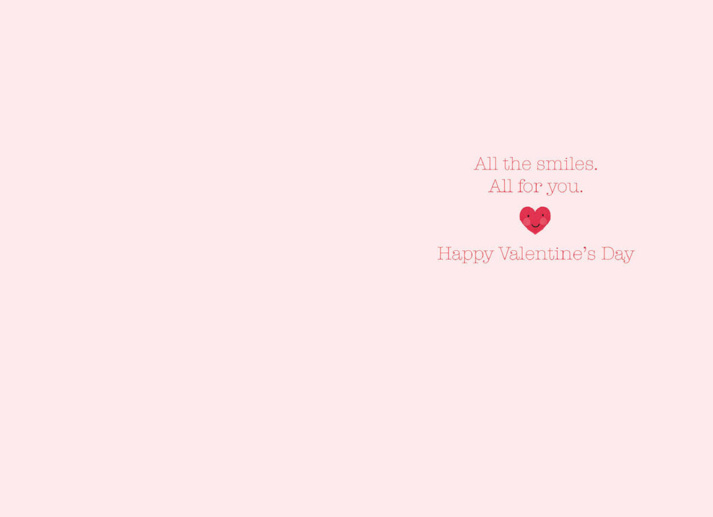 Inside of a light pink greeting card with text 'All the smiles. All for you.' and 'Happy Valentine's Day' accompanied by a small smiling red heart illustration.