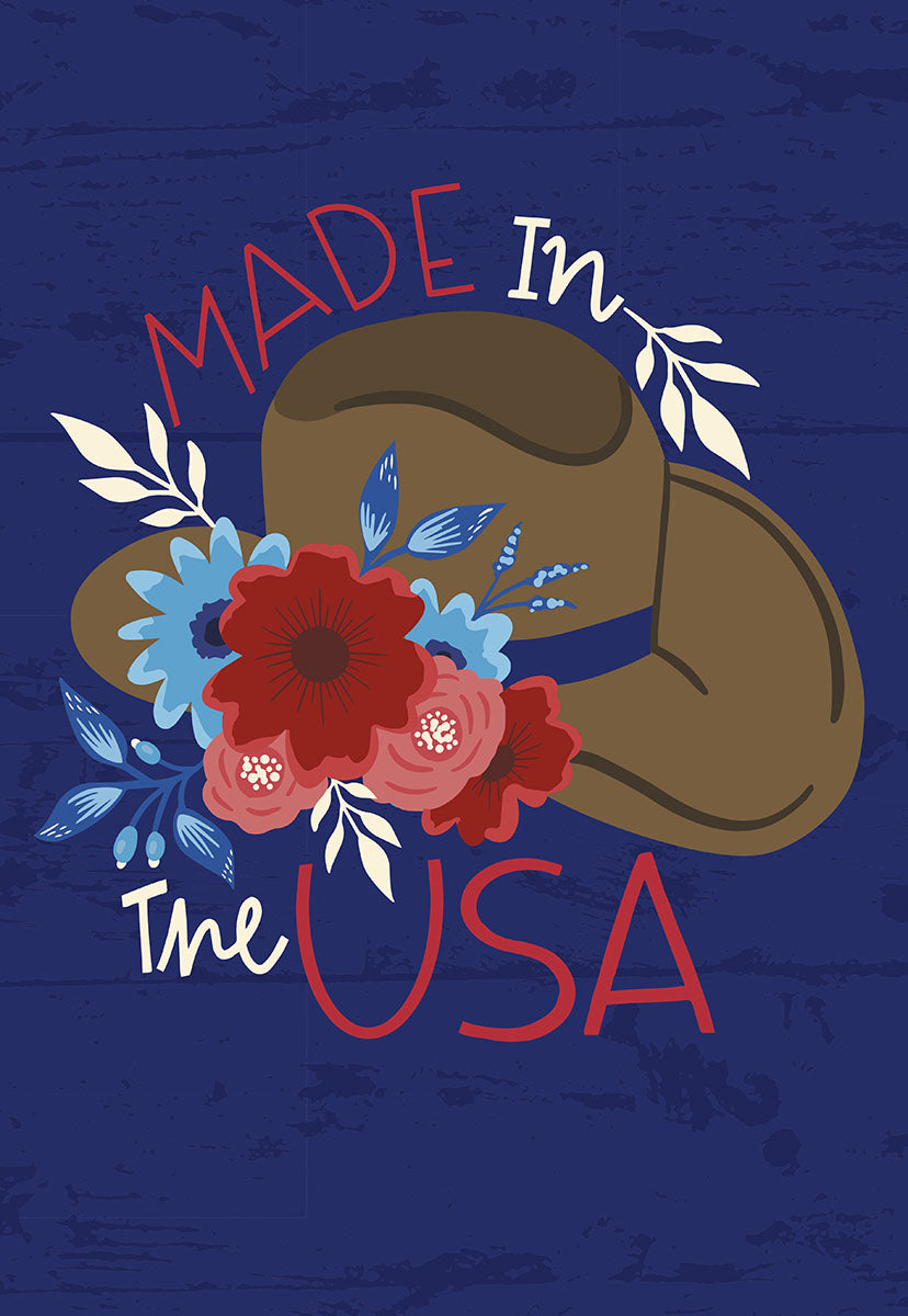 Front of a greeting card with a cowboy hat adorned with red and blue flowers, text "Made In The USA" on blue wood.