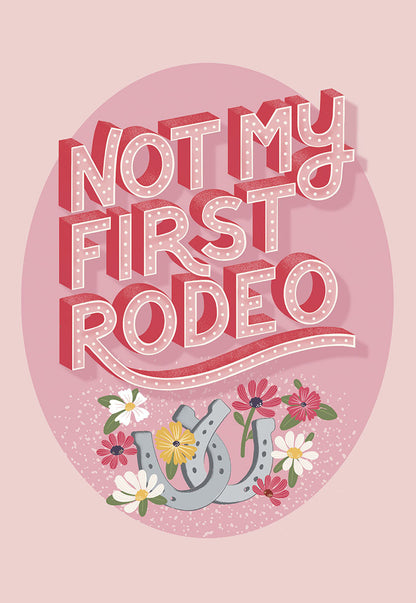 Front of a vibrant pink card with text "NOT MY FIRST RODEO" and two horseshoes surrounded by colorful flowers.