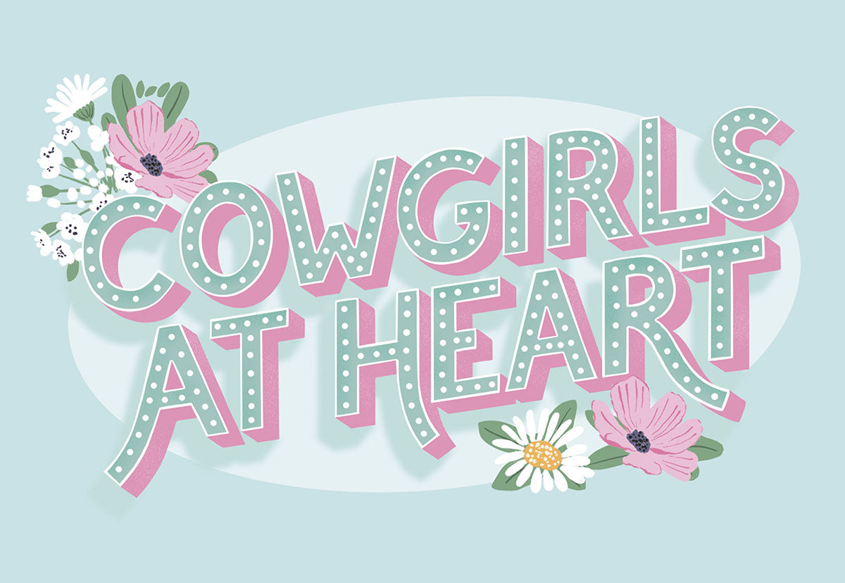 Front of a light blue card with text "COWGIRLS AT HEART" surrounded by pink and white flowers.