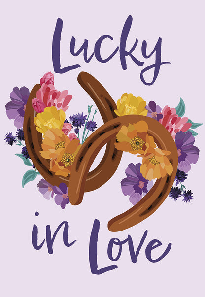 Front of a light purple card with text "Lucky in Love" and two brown horseshoes adorned with colorful flowers.