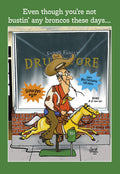 Funny Western-themed birthday card for him, featuring a cartoon old man in a cowboy hat on a coin-operated rocking horse outside a vintage drugstore, with text 'Even though you're not bustin' any broncos these days...'. Perfect humorous card for an older man or grandparent.