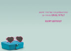 Inside of a sassy greeting card with a light teal background, featuring pink heart sunglasses on a turquoise box. Text reads 'HOPE YOU'RE CELEBRATING IN YOUR USUAL STYLE! HAPPY BIRTHDAY', for a friend.