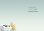 Inside of a serene birthday card with a light blue-green gradient background. Text in pink reads 'TODAY IS ALL ABOUT YOU! HAPPY BIRTHDAY'. White rolled towels with cucumber slices and lit candles are in the foreground.