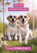 Two happy Labrador dogs wearing pink and yellow heart-shaped sunglasses, sitting on a wooden swing under blooming trees. The card reads: "ANY DAY I SPEND WITH YOU IS MY FAVORITE DAY!"