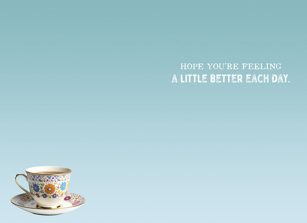 Inside of a light blue greeting card showing a small floral teacup and saucer in the bottom left. The message 'HOPE YOU'RE FEELING A LITTLE BETTER EACH DAY.' is centered on the right side.