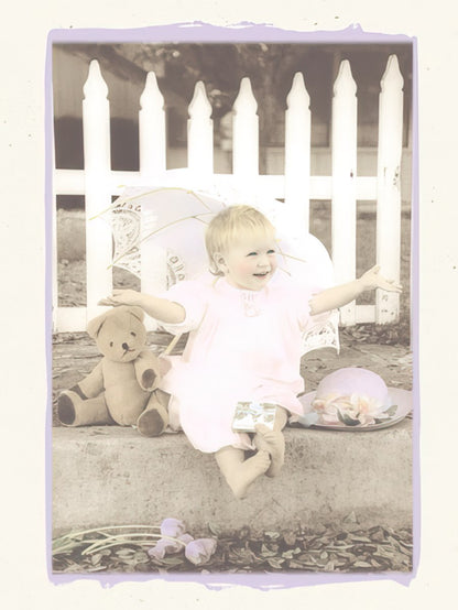 Greeting card front showing a happy little girl in pink with a teddy bear by a white picket fence.