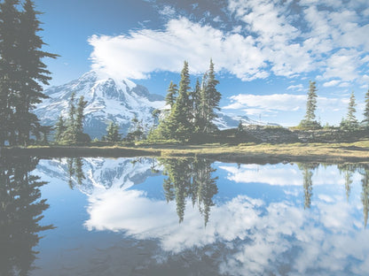 A serene mountain lake perfectly reflecting a snow-capped peak and a clear blue sky with fluffy white clouds.