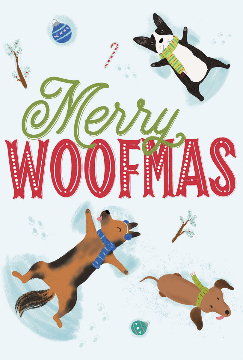 Front of a playful greeting card featuring three cartoon dogs making snow angels, festive blue and red ornaments, candy canes, and bare winter branches. The text "Merry Woofmas" is prominently displayed in green and red lettering on a light blue background.