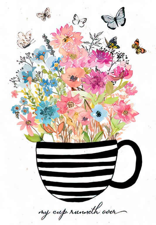 Front of a religious birthday card with a black and white striped teacup overflowing with colorful watercolor flowers and butterflies. Text reads 'my cup runneth over'.