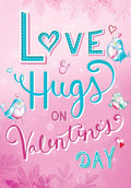 Front of a vibrant pink greeting card featuring 'Love & Hugs' in playful teal and pink fonts, adorned with three charming cartoon love birds and delicate hearts, all against a soft floral background, perfect for a loved one.