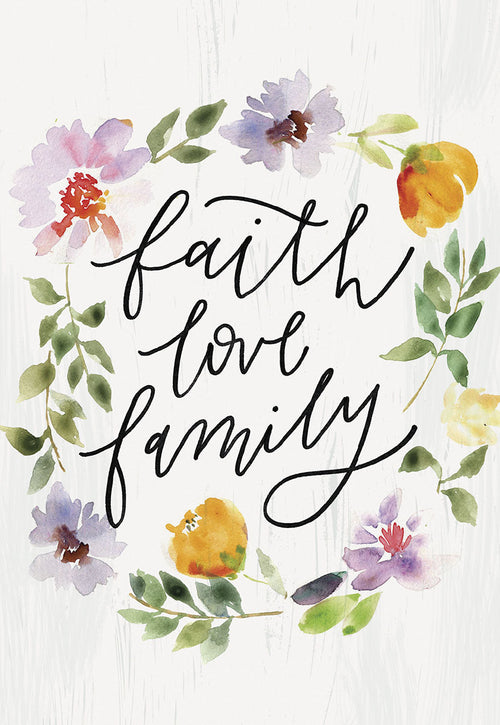 Front of a religious anniversary greeting card featuring a watercolor floral wreath surrounding the script words 'faith love family' on a white wood texture background.