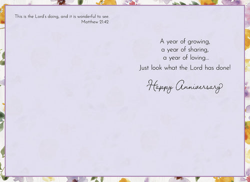Inside of a religious anniversary card displaying Bible verse Matthew 21:42 and a heartfelt message 'A year of growing, a year of sharing, a year of loving... Just look what the Lord has done! Happy Anniversary' with watercolor floral border.