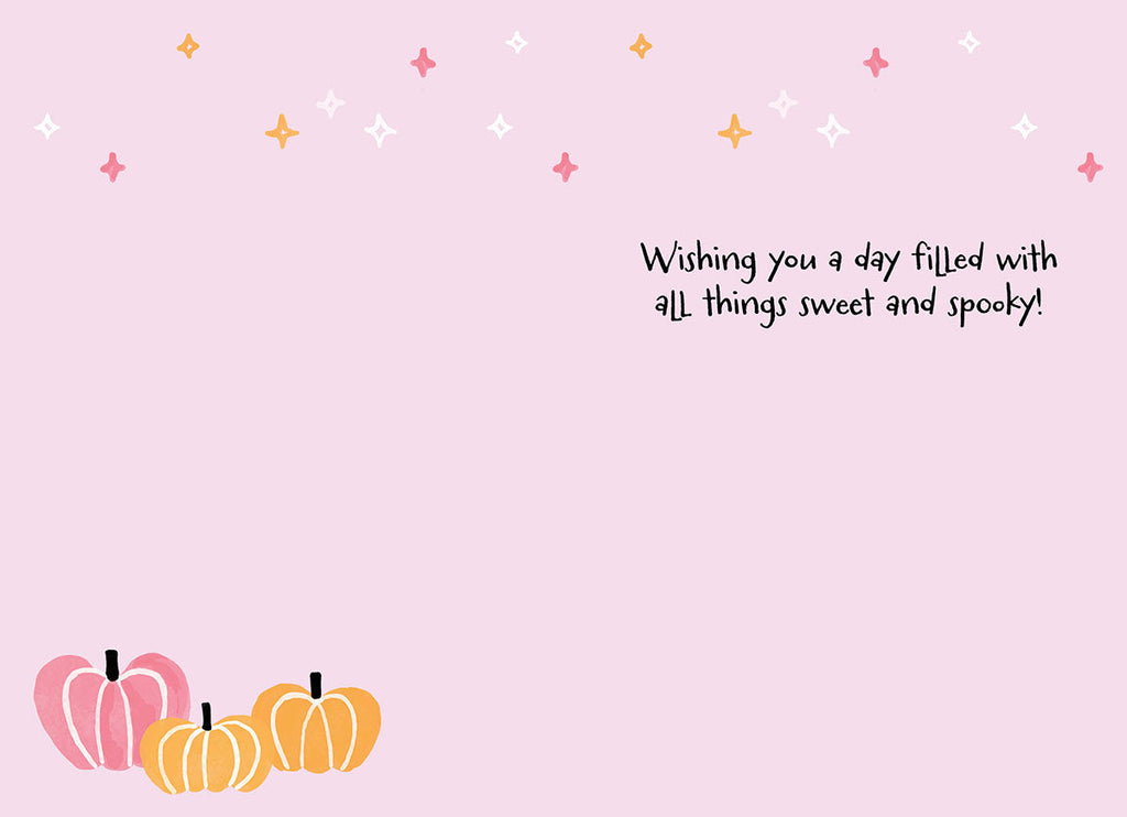 Inside of a pastel pink Halloween greeting card featuring sparkling star accents and a small cluster of pink and orange pumpkins at the bottom. Handwritten text reads: 'Wishing you a day filled with all things sweet and spooky!'.