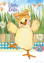 Front of a cheerful Easter greeting card featuring a fluffy yellow chick wearing an orange striped bow on its head, standing in a vibrant green grassy field with colorful flowers and a blue sky background. The text 'Happy Easter' is prominently displayed in purple script. An adorned Easter egg rests at the bottom.