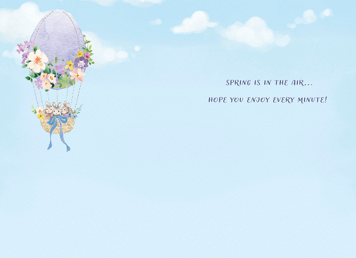 Inside view of a charming spring greeting card showing the continued watercolor hot air balloon design on the left, with text 'SPRING IS IN THE AIR... HOPE YOU ENJOY EVERY MINUTE!' on the right, set against a serene blue sky background.