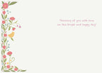 Interior of an elegant holiday card, showcasing a border of pink flowers, green foliage, and a yellow bird, with a printed message: 'Thinking of you with love on this bright and happy day!'