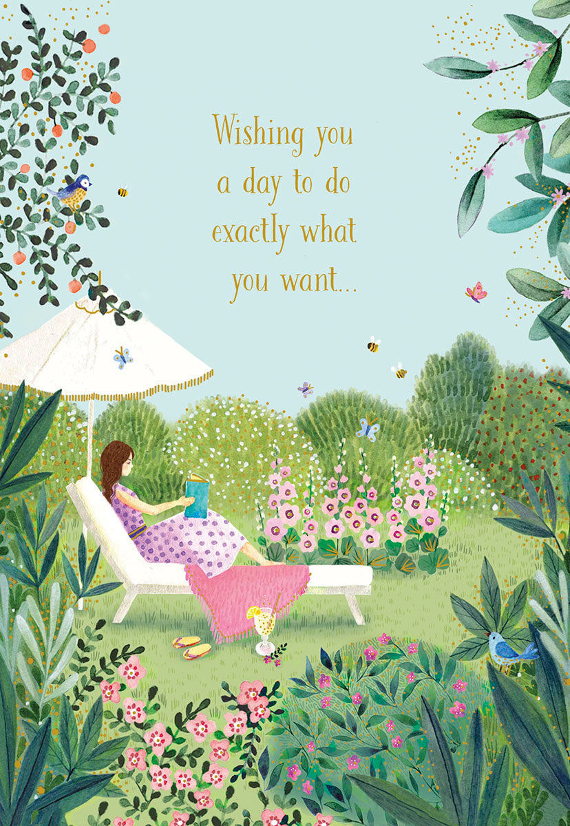 Elegant Mother's Day greeting card showing a peaceful garden scene with a woman relaxing in a lounge chair under an umbrella, reading a book amidst flowers, birds, and butterflies. Text reads: 'Wishing you a day to do exactly what you want...'