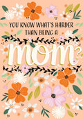 Illustrated Mother's Day greeting card front with vibrant orange, white, and purple flowers and bold text 'YOU KNOW WHAT'S HARDER THAN BEING A MOM?' on a peach background, perfect for showing appreciation to her.