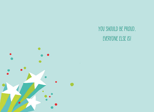 Inside of a light blue graduation card featuring white stars, colorful dots, and the encouraging message: 'YOU SHOULD BE PROUD. EVERYONE ELSE IS!'