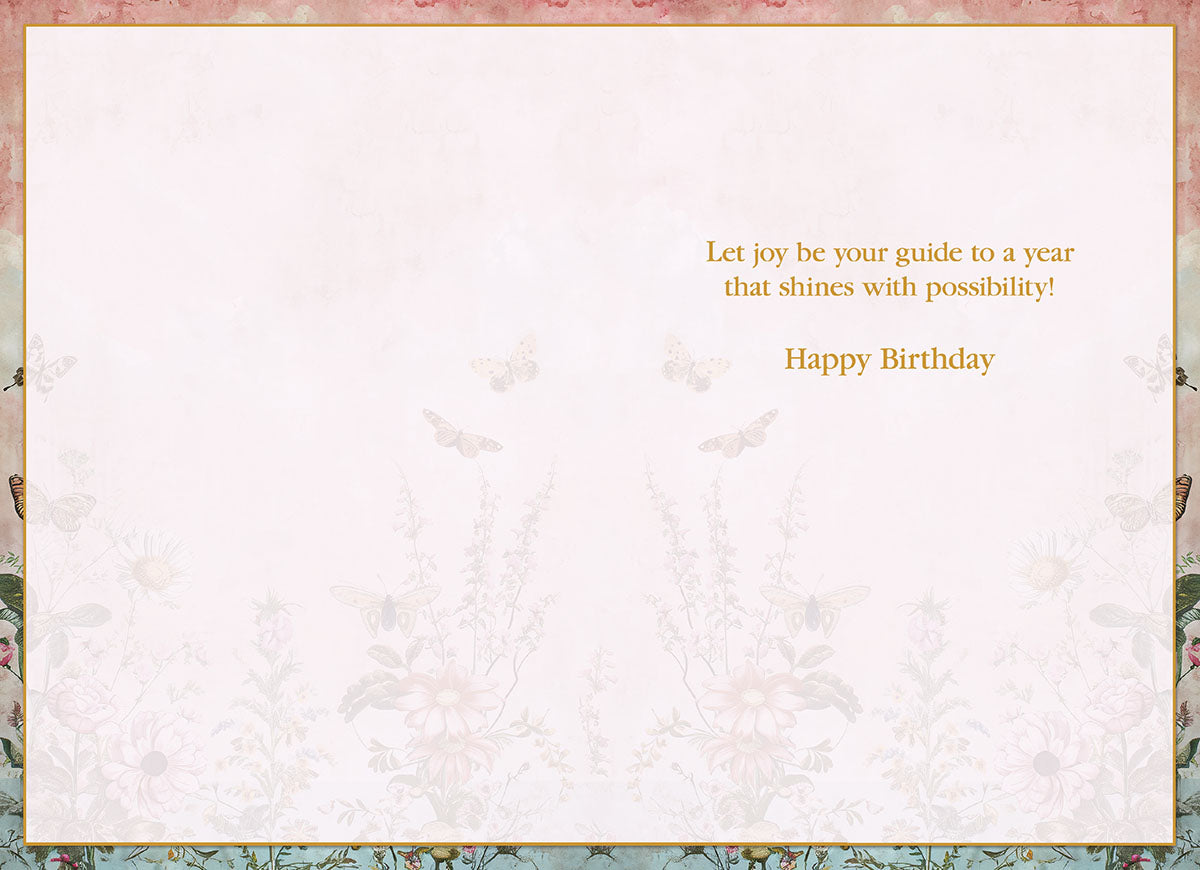Interior of an elegant greeting card, showing a blank space for a personal message, bordered by a floral and butterfly motif. Printed message reads: 'Let joy be your guide to a year that shines with possibility! Happy Birthday'.